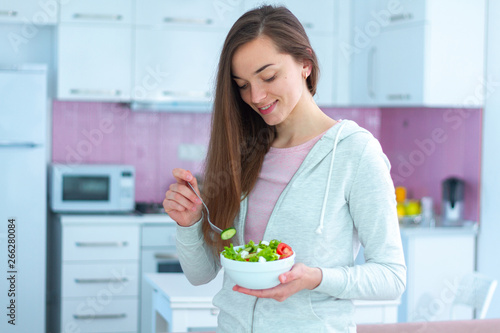 Young happy beautiful vegetarian woman eating vegetables salad for snack at home. Diet and fitness eating. Clean and healthy food