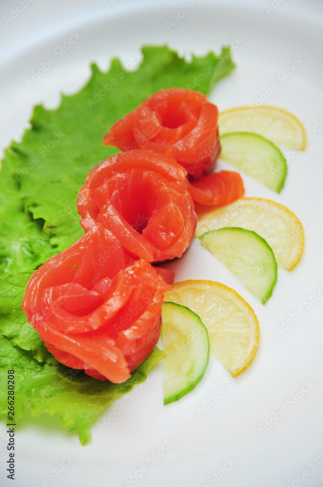 Fresh salmon decorative roses fillets, with lemon slices on the plate Fresh salmon decorative roses fillets, with lemon slices on the plate