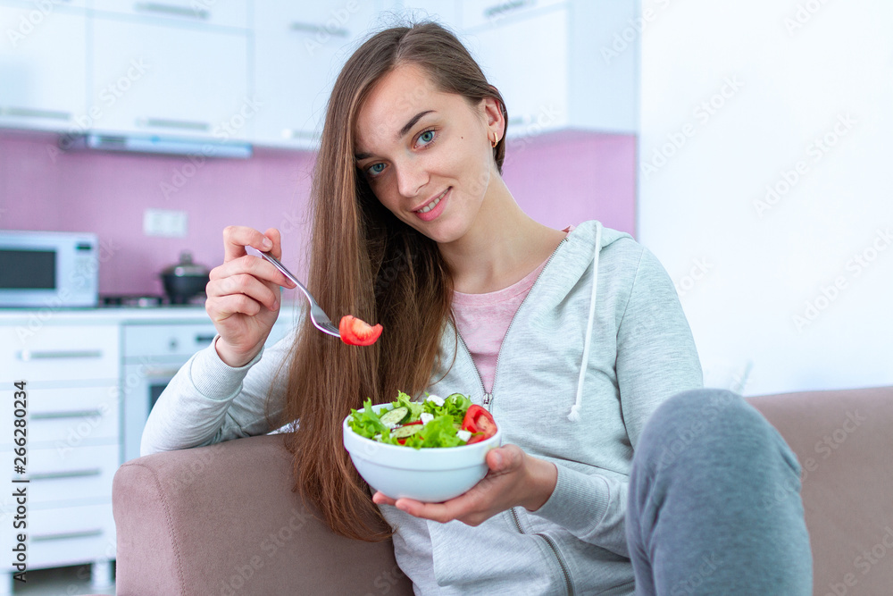 Portrait of young happy healthy woman eating vegetable salad for lunch at home. Diet and fitness eating. Clean and control food Portrait of young happy healthy woman eating vegetable salad for lunch at home. Diet and fitness eating. Clean and control food