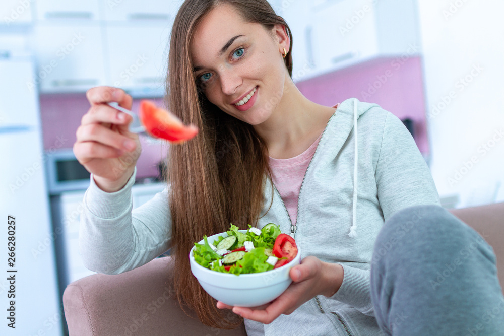 Portrait of young happy healthy woman eating vegetable salad for lunch at home. Diet and fitness eating. Clean and control food