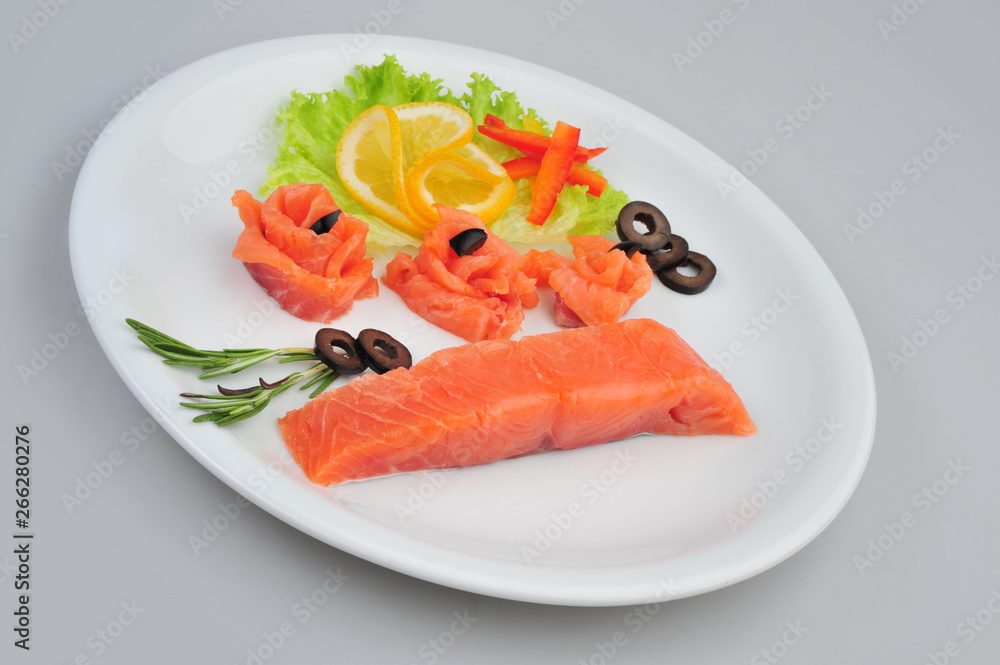 Fresh salmon decorative roses fillets, with lemon, olives on the plate. Isolated on a gray background