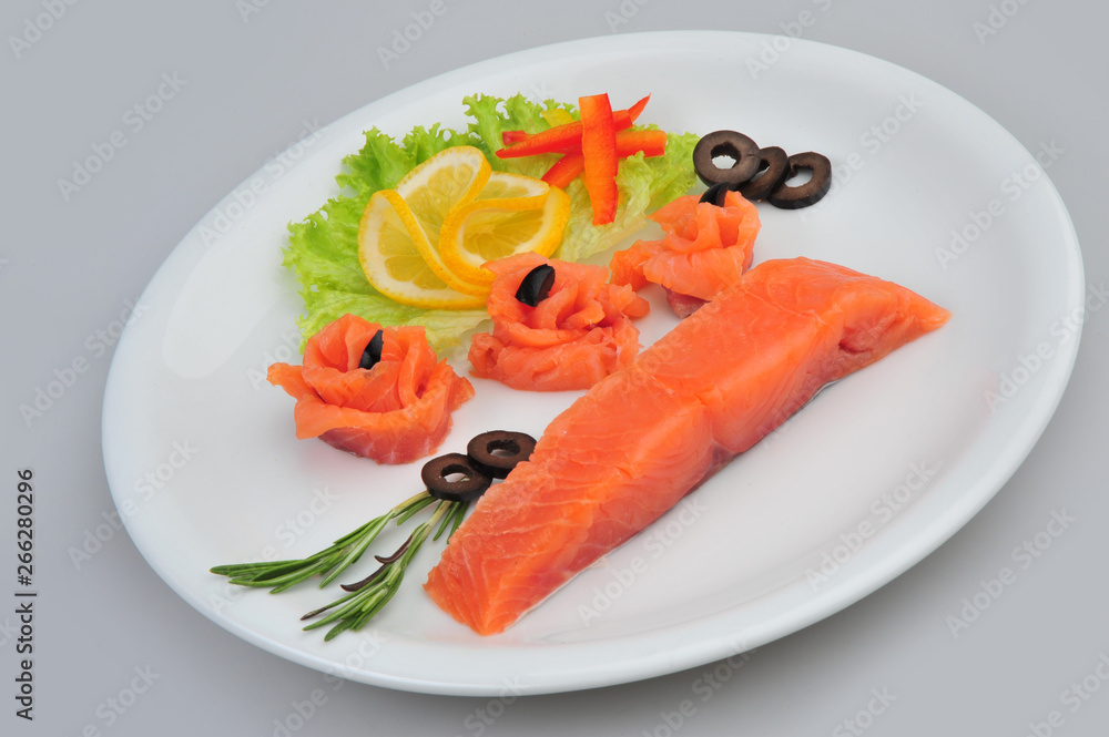 Fresh salmon decorative roses fillets, with lemon, olives on the plate. Isolated on a gray background Fresh salmon decorative roses fillets, with lemon, olives on the plate. Isolated on a gray background