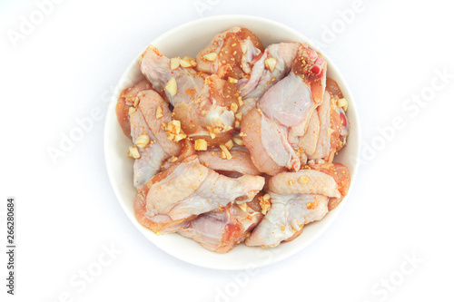 Fresh pickled chicken wings lie in a white plate. Chicken marinated with garlic, pepper and spices, on a white background.