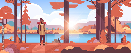 male tourist hiker with backpack man traveler holding stick standing in forest hiking concept sunrise autumn landscape nature river mountains background flat horizontal full length flat