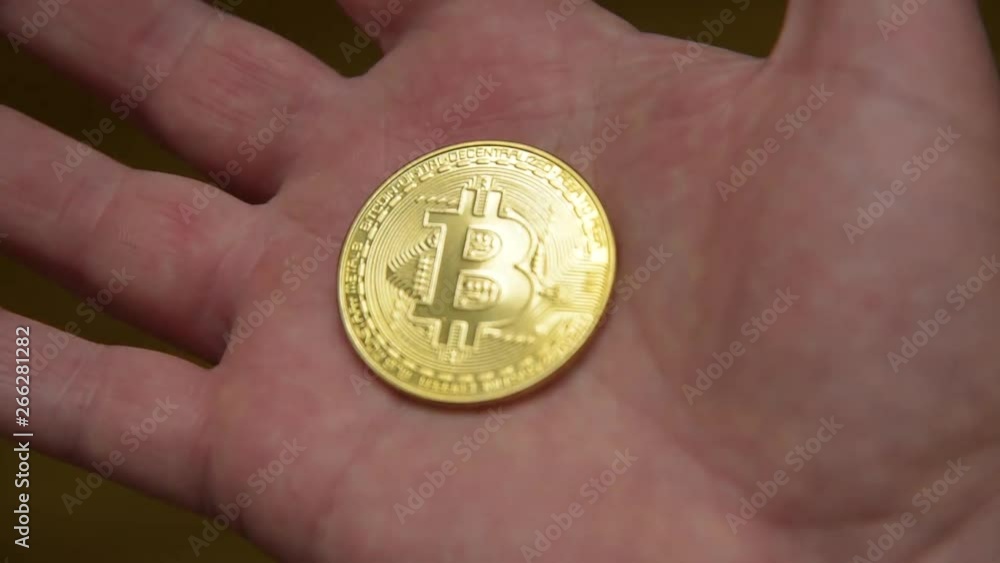 Gold bitcoin coin on the male palm which is squeezed into a fist. Bitcoin business concept. Close up of bit coin in hand. Investment in bitcoin cryptocurrency business. Global blockchain technology Gold bitcoin coin on the male palm which is squeezed into a fist. Bitcoin business concept. Close up of bit coin in hand. Investment in bitcoin cryptocurrency business. Global blockchain technology
