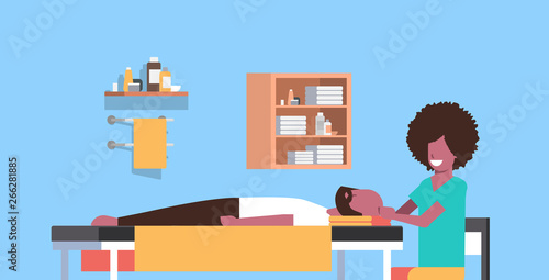 young man having head massage african american masseuse massaging patient body guy relaxing lying on table luxury spa salon treatments concept horizontal