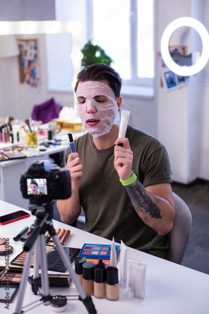 Inspired attentive man moisturizing skin with fresh mask