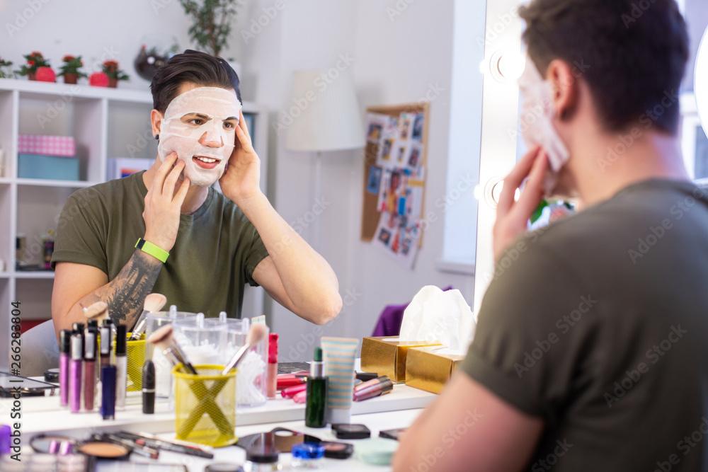 Satisfied short-haired vlogger touching his face mask Satisfied short-haired vlogger touching his face mask