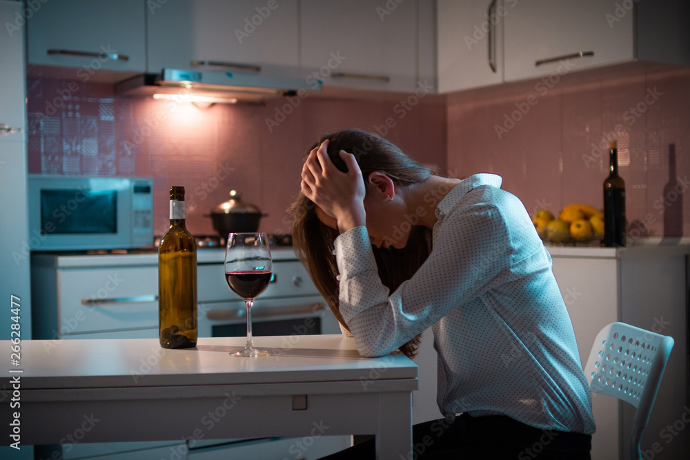 Unhappy, lonely stressed woman with red wine is drinking alone in the  kitchen in evening. Life difficulties and problems. Female alcoholism and  alcohol addiction Stock Photo | Adobe Stock