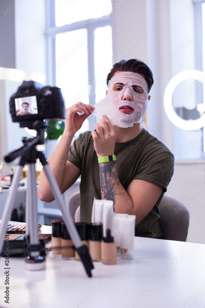 Strong tattooed young man being a professional beauty blogger Strong tattooed young man being a professional beauty blogger