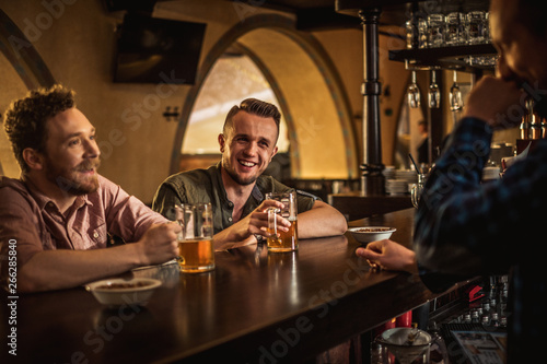 Cheerful friends drinking draft beer in a pub