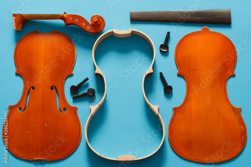 Luthier violin disassembled and all parts are laid out in order: body, back and front plates, ribs, blocks, scroll, peg, head, shaft, fingerboard, neck.