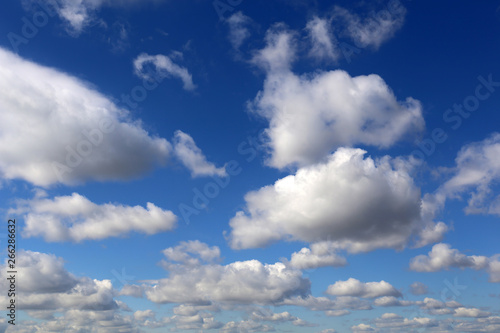 Blue sky covered with white cumulus clouds. Spring cloudscape, beautiful background for good sunny weather