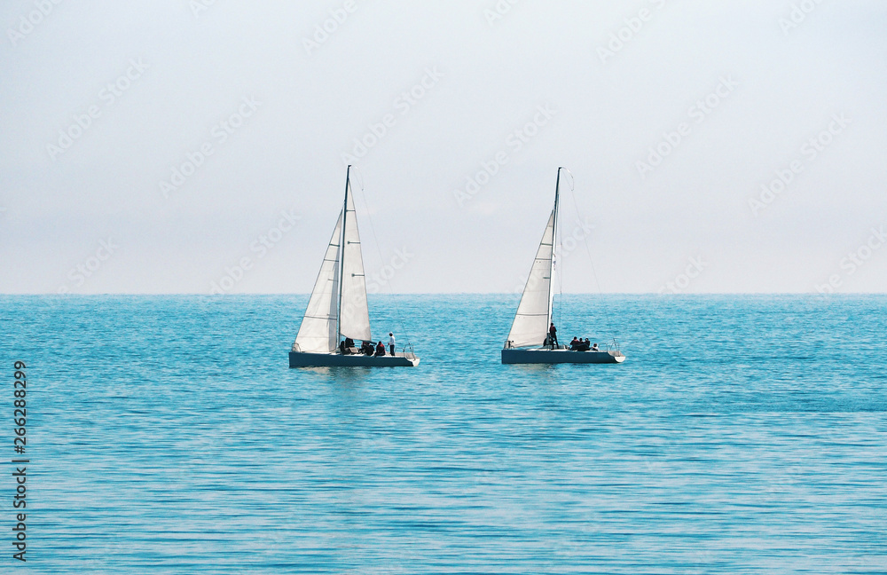 Sailing boats for regatta at blue sea and sky background