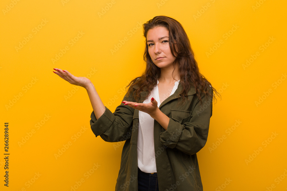 Young european woman isolated over yellow background doubting between two options. Young european woman isolated over yellow background doubting between two options.
