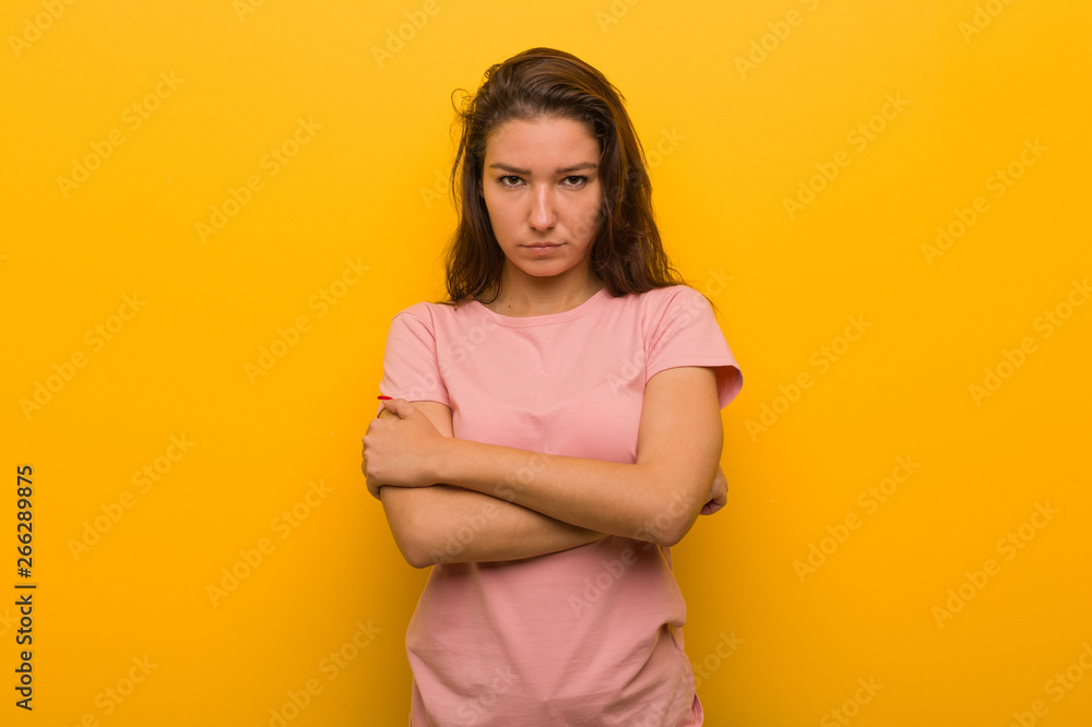 Young european woman isolated over yellow background frowning her face in displeasure, keeps arms folded. Young european woman isolated over yellow background frowning her face in displeasure, keeps arms folded.