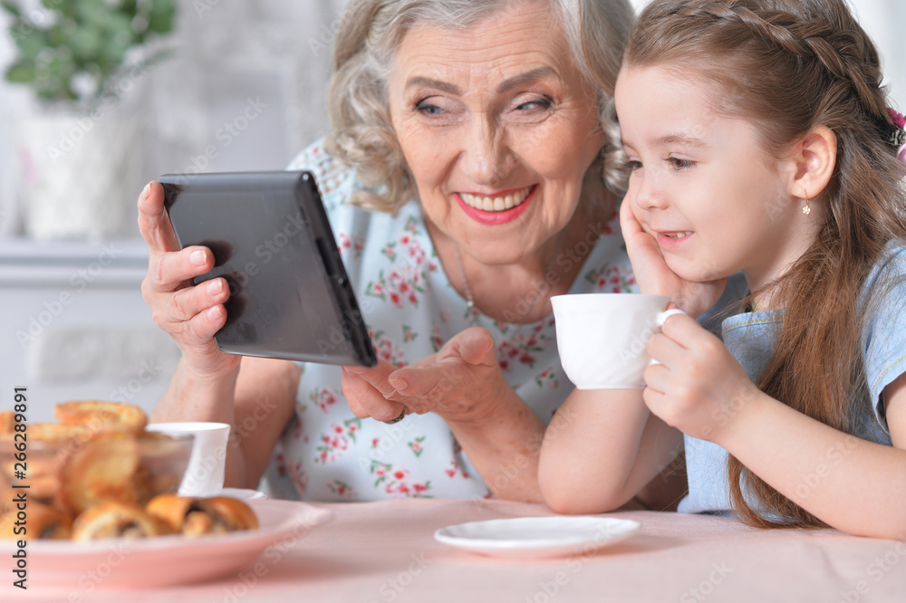 Cute little girl with her grandmother looking at tablet Cute little girl with her grandmother looking at tablet