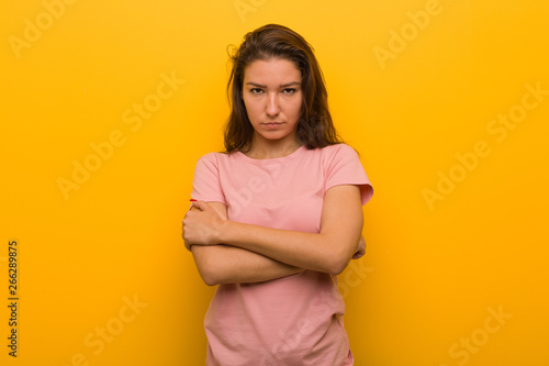 Young european woman isolated over yellow background frowning her face in displeasure, keeps arms folded.