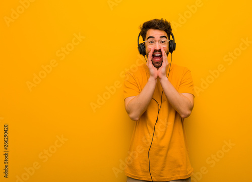 Young man listening to music shouting something happy to the front