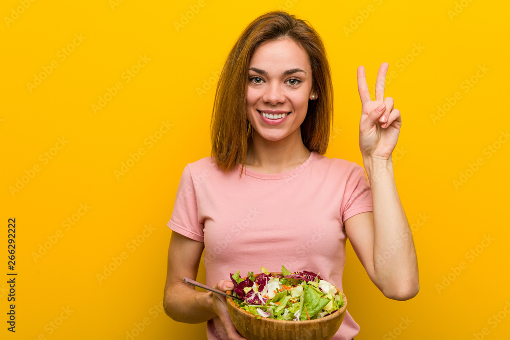 Young healthy woman holding a salad showing number two with fingers. Young healthy woman holding a salad showing number two with fingers.