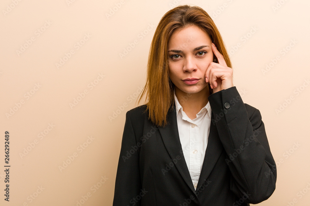 Young caucasian business woman pointing her temple with finger, thinking, focused on a task. Young caucasian business woman pointing her temple with finger, thinking, focused on a task.