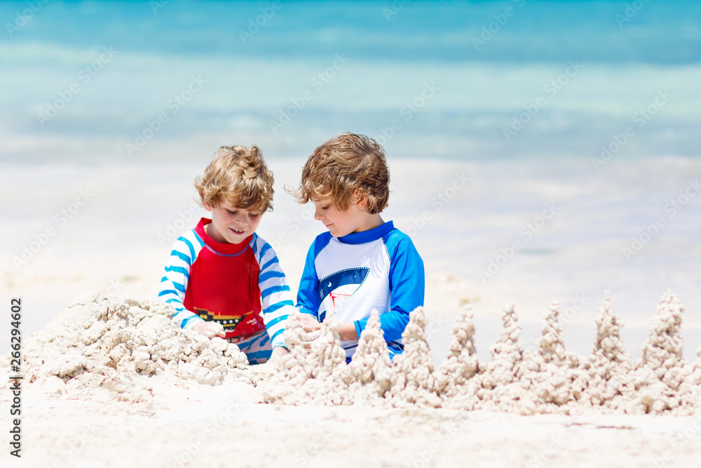 Two kid boys building sand castle on tropical beach of Playa del Carmen, Mexico
