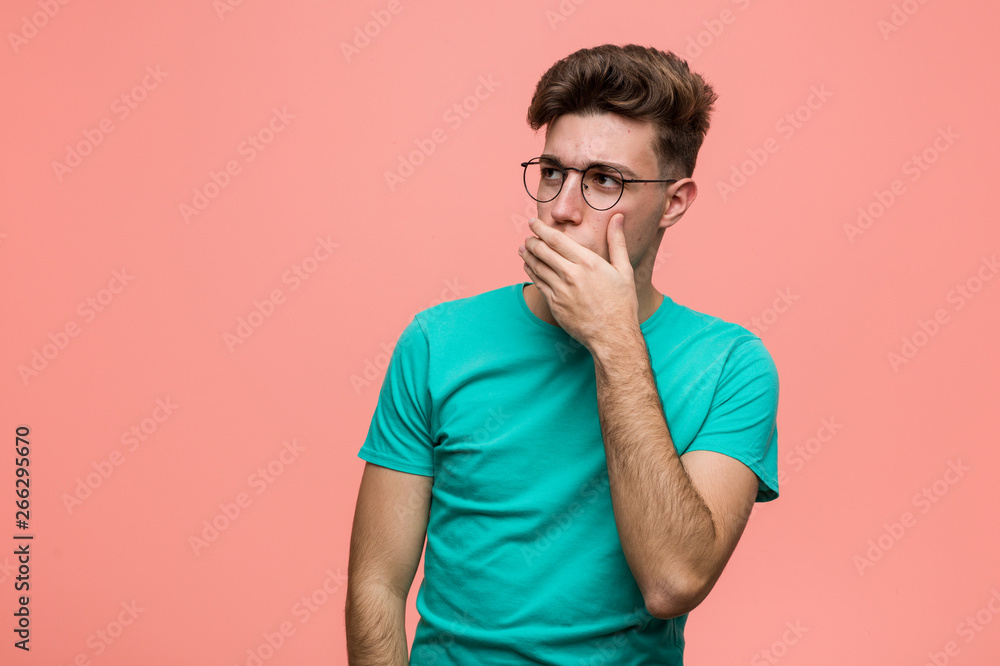 Young cool caucasian man thoughtful looking to a copy space covering mouth with hand. Young cool caucasian man thoughtful looking to a copy space covering mouth with hand.
