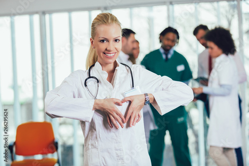 Portrait of a female doctor showing heart gesture with hands photo