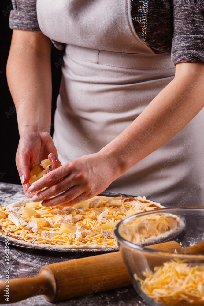 young woman in a gray aprons prepares a Hawaiian pizza young woman in a gray aprons prepares a Hawaiian pizza