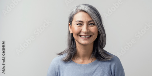 Fototapeta Beautiful asian with grey hair smiling standing near the wall