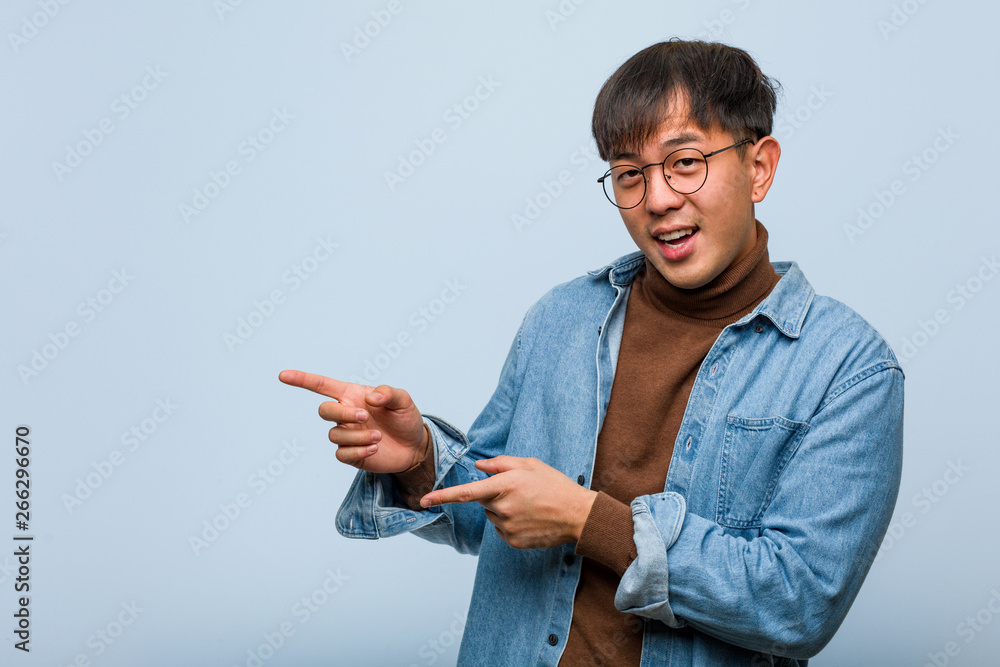 Young chinese man pointing to the side with finger Young chinese man pointing to the side with finger