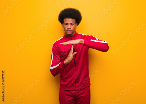 Young sport black man over an orange wall doing a timeout gesture
