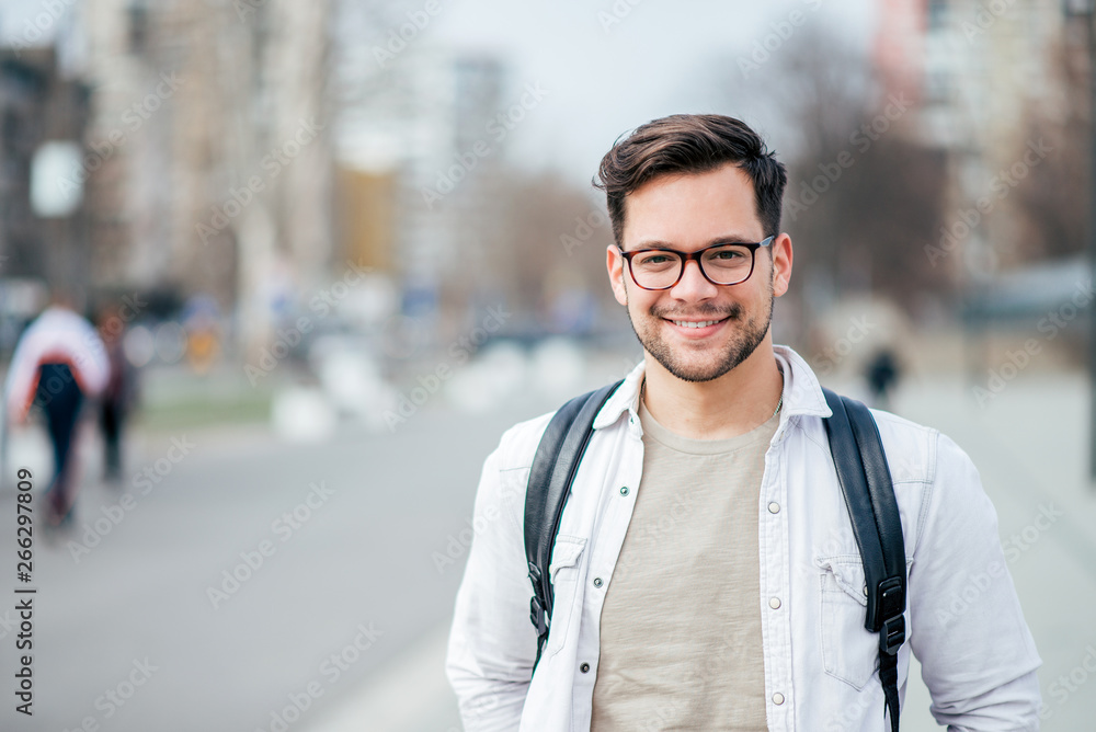 Portrait of a smiling student at the city street. - obrazy, fototapety, plakaty 