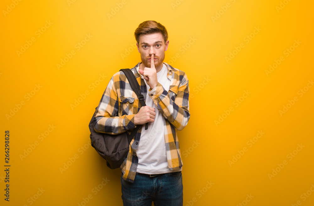 Young redhead student man keeping a secret or asking for silence Young redhead student man keeping a secret or asking for silence