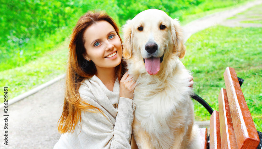 Portrait happy owner woman hugging her Golden Retriever dog in city park Portrait happy owner woman hugging her Golden Retriever dog in city park