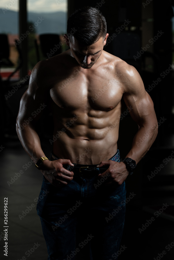 Young Bodybuilder In Jeans Flexing Muscles
