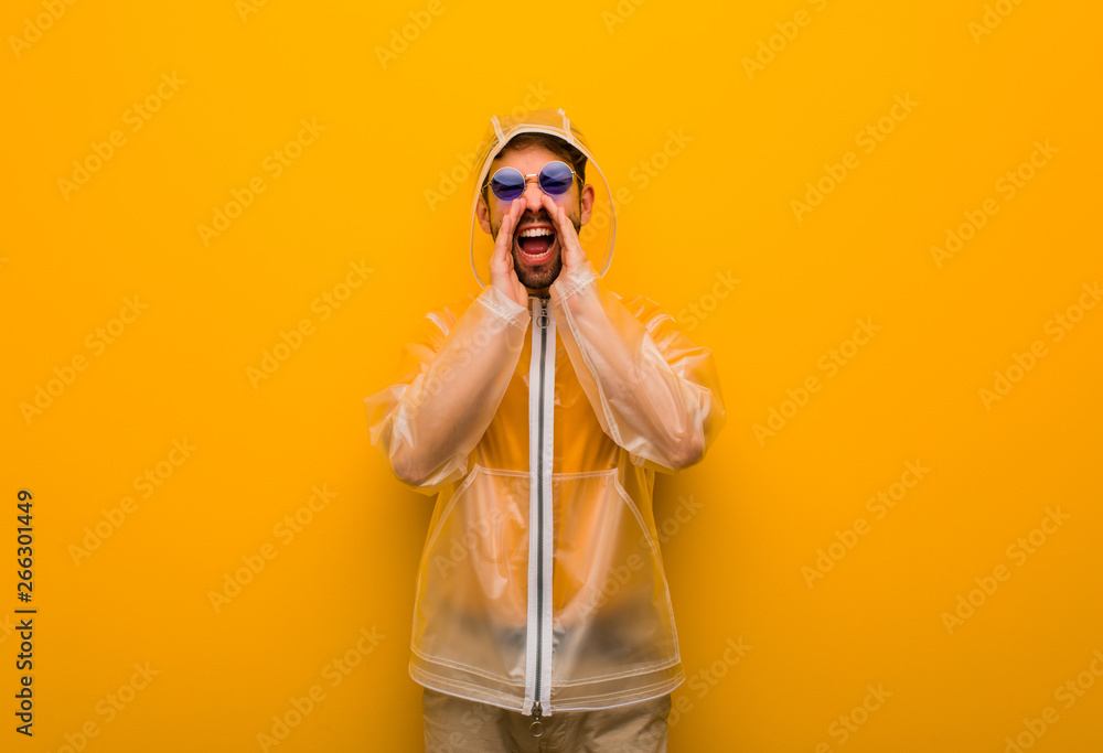 Young man wearing a rain coat shouting something happy to the front Young man wearing a rain coat shouting something happy to the front