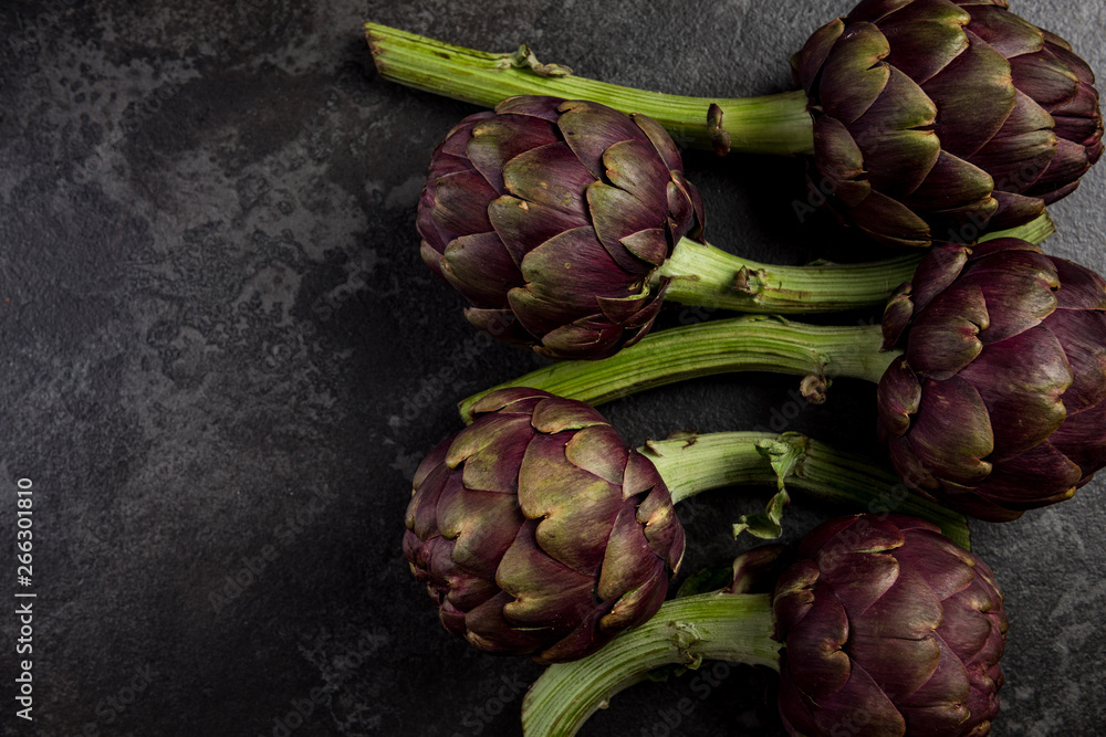 Obraz premium Purple artichokes flowers heads on dark slate