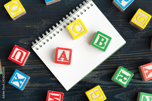 Notepad on wooden table and wood alphabet blocks