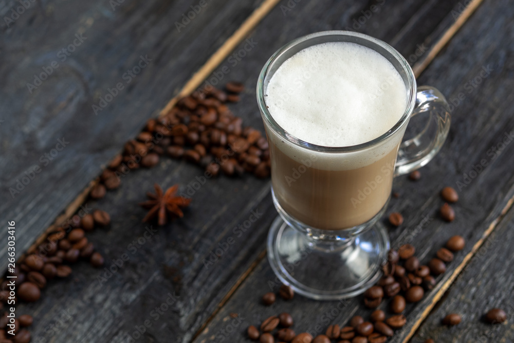 Coffee with milk in a glass on a wooden table with roasted coffee beans Coffee with milk in a glass on a wooden table with roasted coffee beans