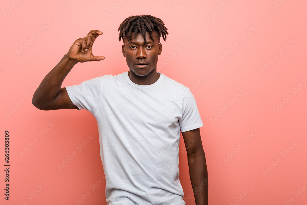 Young african black man holding something little with forefingers, smiling and confident. Young african black man holding something little with forefingers, smiling and confident.