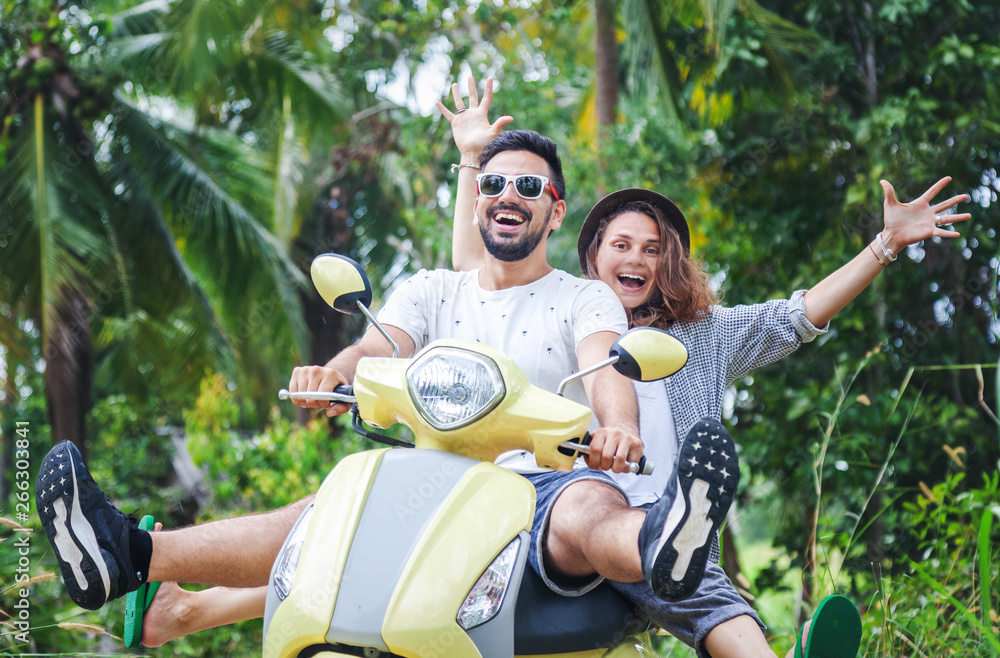 Happy multinational couple traveling on a motorbike in the jungle, honeymoon, vacation, travel concept, friends have fun