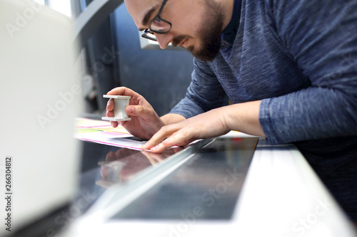 The printer at the stage watches the print quality through a magnifying glass. photo