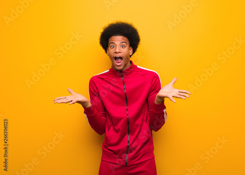 Фотография Young sport black man over an orange wall celebrating a victory or success