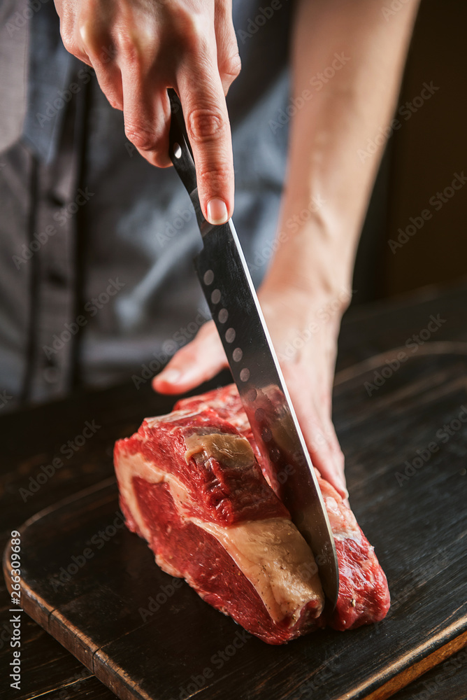 cook cuts raw meat for steaks