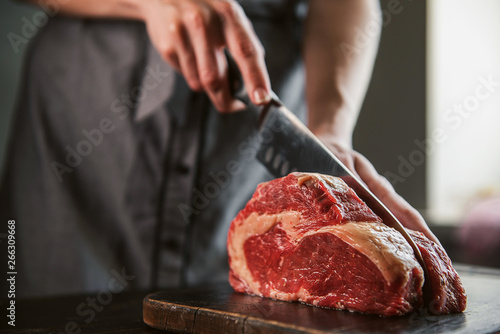 Obraz na płótnie cook cuts raw meat for steaks w salonie