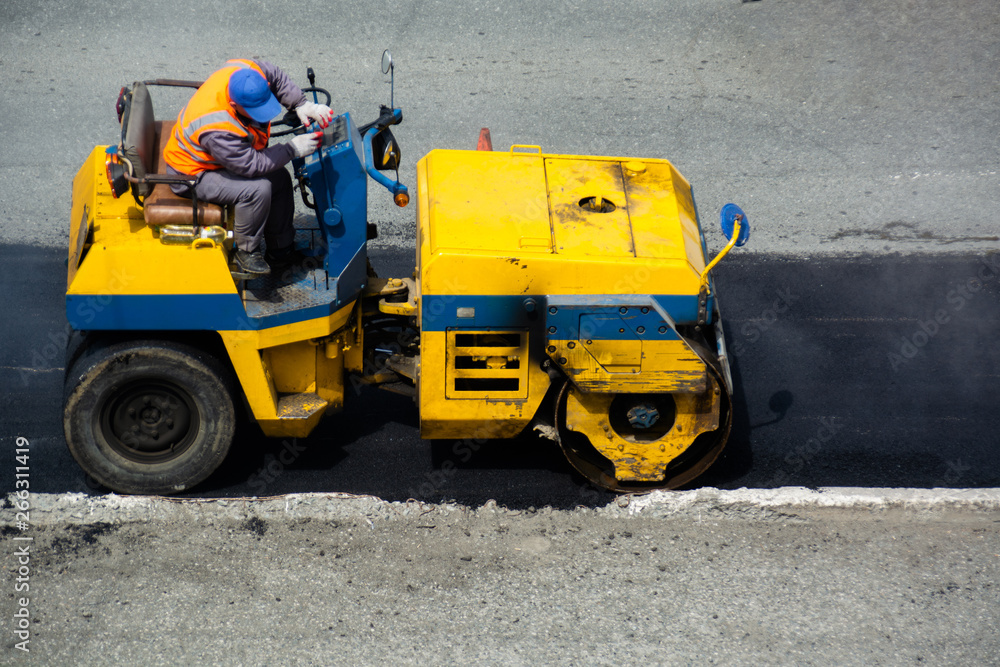 Driver of road roller leveling new layer of asphalt. Not large machine in  yellow and blue colors. Road roller without the cabine. Stock Photo | Adobe  Stock