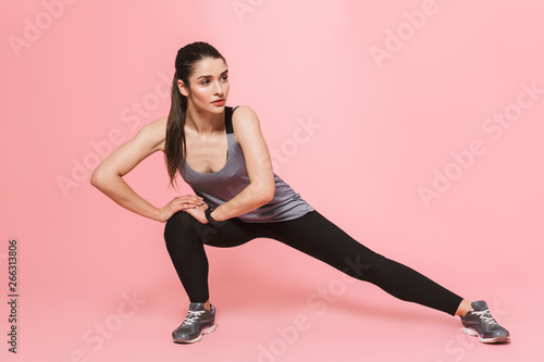 Amazing beautiful young pretty fitness woman make sport exercises isolated over pink wall background.