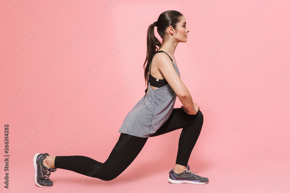 Amazing beautiful young pretty fitness woman make sport exercises isolated over pink wall background.