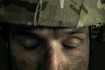 Empty eyes wanna be closed. Close up portrait of young male soldier. Man in military uniform on the war. Depressed and having problems with mental health and emotions, PTSD, rehabilitation.